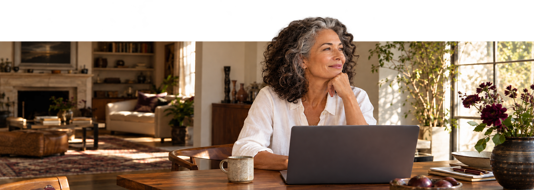 Illustrative portrait of a woman beside her laptop in a warmly lit home, with her full head extending above the photograph’s frame.